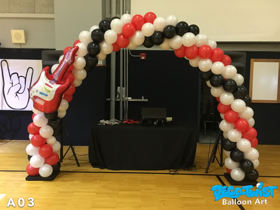 A balloon arch made of red, black, and white balloons stands indoors. On the left side, a large balloon guitar decoration is attached, giving the display a fun rock-and-roll theme.