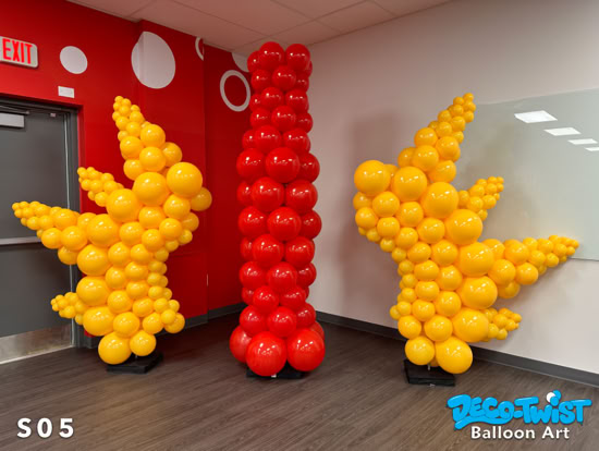 A balloon sculpture displays the Coca-Cola Florida logo, featuring a tall red column shaped like Coke bottle in the center and a large yellow starburst-shaped balloon design on each side.